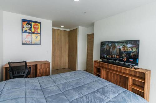 1 dormitorio con 1 cama y TV de pantalla plana en Suite lujosa Edificio One piso 21 Quito- Ecuador, en Quito