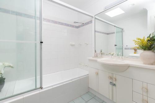 a white bathroom with a shower and a sink at The Reef in Boomerang Beach
