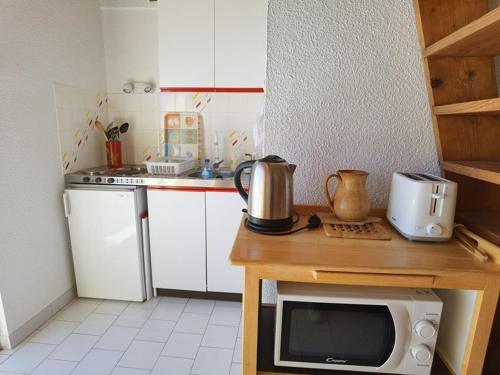 une cuisine avec un four micro-ondes au-dessus d'une table dans l'établissement Appartement cosy avec mezzanine, 5 couchages, parking privé - FR-1-326-688, à Marseillan