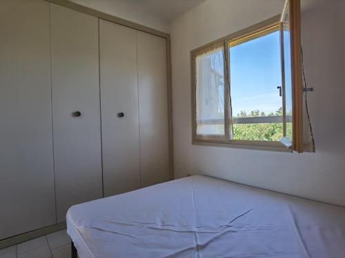 une chambre blanche avec un lit et une fenêtre dans l'établissement Appartement cosy avec mezzanine, 5 couchages, parking privé - FR-1-326-688, à Marseillan