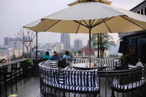 a patio with tables and chairs with an umbrella at JM Marvel Hotel & Spa in Hanoi