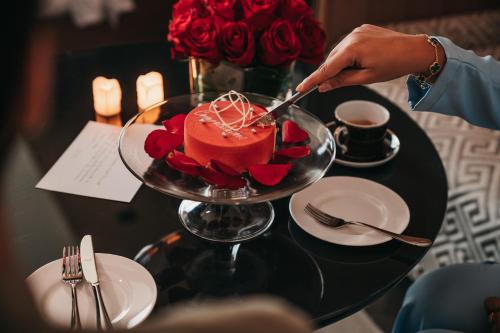 a person cutting a cake on a table with roses at Four Seasons Hotel Kuwait at Burj Alshaya in Kuwait