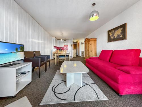 a living room with a red couch and a tv at Les Mayens de l'Ours - At the foot of Piste de l'Ours' slope! in Agettes