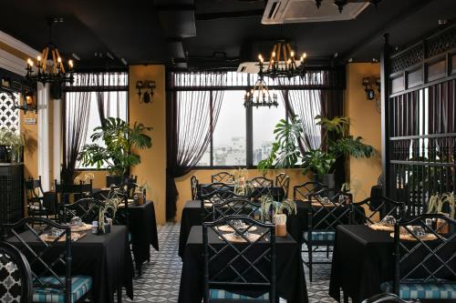 a restaurant with black tables and chairs and windows at JM Marvel Hotel & Spa in Hanoi