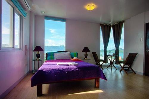a bedroom with a purple bed and a large window at Haven 1916 Pension House in Coron