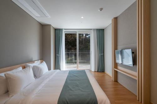 a bedroom with a large bed and a window at Hanwha Resort Geoje Belvedere in Geoje 