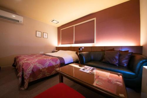 a hotel room with a bed and a couch at Hotel Vanilla (Adult Only) in Ueda