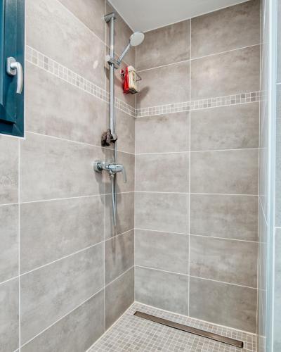 La salle de bains est pourvue d'une cabine de douche et d'un mur carrelé. dans l'établissement Ô Fil de l'Eau - Appartement standing vue mer A08 T2, à Bandol