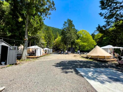 un groupe de tentes et une route arborée dans l'établissement リバーサイドグランピングNuts, à Higashiomi