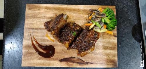a wooden cutting board with steak and vegetables on it at Hotel Polo Towers Shillong in Shillong