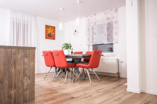 a dining room with a table and red chairs at Apartma Tia 2 in Zreče