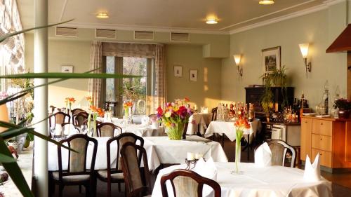 ein Esszimmer mit Tischen und Stühlen mit Blumen in der Unterkunft Restaurant und Hotel Zum Weissen Ross in Mölln