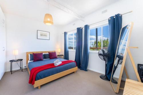 een slaapkamer met een bed met blauwe gordijnen en een raam bij Syds Place A 70s retro beach house Free WIFI in Goolwa South