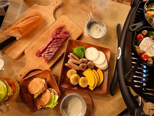 a table with two cutting boards with different types of food at リバーサイドグランピングNuts in Higashiomi