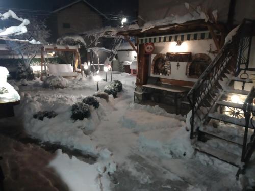a snow covered yard with a house with a staircase at NIKI HOUSE in Bansko