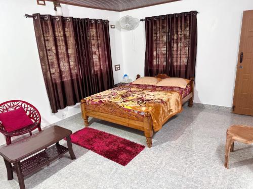 a bedroom with a bed and a table and a chair at Hill View Homestay Madikeri Coorg 3BHK Villa in Madikeri