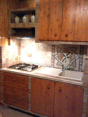 a kitchen with wooden cabinets and a sink and a stove at Casa vacanza a 1km dalla funivia in Chiesa in Valmalenco