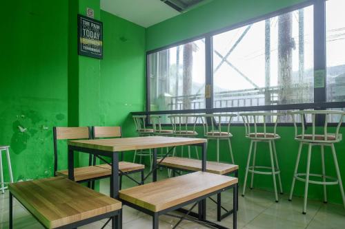 uma sala verde com mesas e cadeiras de madeira em RedDoorz near Politeknik Manado em Paniki