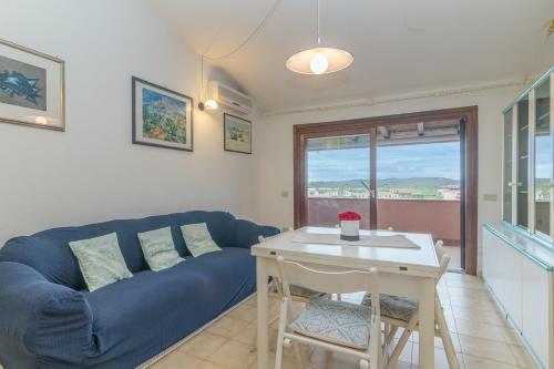 een woonkamer met een blauwe bank en een tafel bij I Fari 48 600Mt From The Beach - Happy Rentals in Porto San Paolo