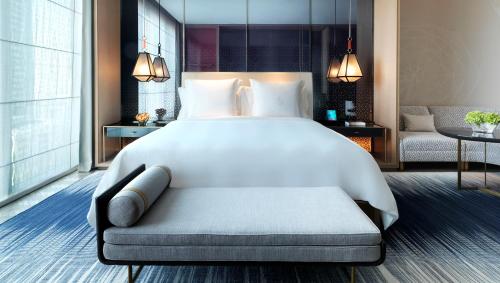 a bedroom with a large white bed and a living room at Four Seasons Hotel Kuwait at Burj Alshaya in Kuwait