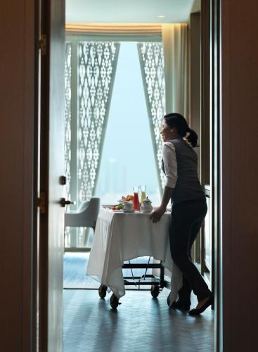 a woman standing at a table in a room at Four Seasons Hotel Kuwait at Burj Alshaya in Kuwait