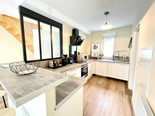 une grande cuisine avec des placards blancs et une grande fenêtre dans l'établissement Sea, Surf and Sun, à Saint-Pierre-Quiberon