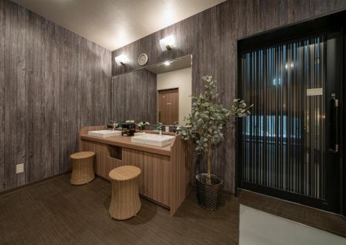 a bathroom with a sink and a mirror and stools at Hotel Route Inn Osaka Izumifuchu in Izumi