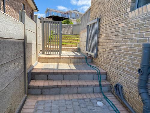 a stairway with a hose attached to a brick wall at Tulip On The Bay in Mossel Bay