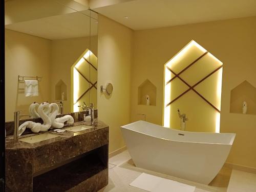 a bathroom with a large tub and a large mirror at Sidra Resort in Buqayq