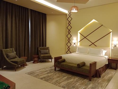 a bedroom with a bed and two chairs in it at Sidra Resort in Buqayq