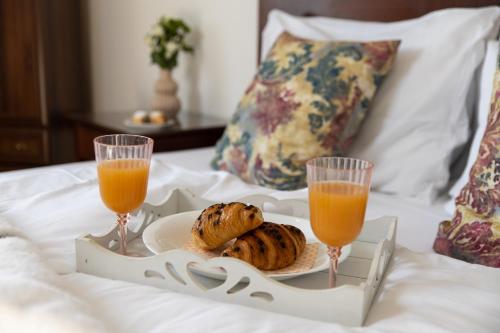 two glasses of orange juice and a plate of food on a bed at Continentale - Deluxe Rooms in Rijeka