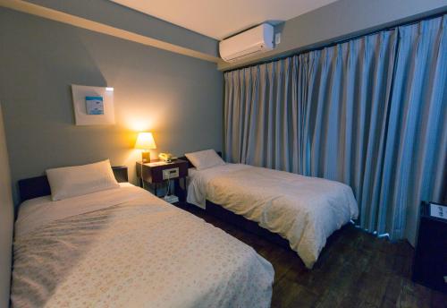 a hotel room with two beds and a window at Tsushima Dae-A Hotel in Tsushima