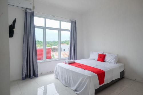 a bedroom with a bed with a large window at RedDoorz near De La Salle Manado in Manado