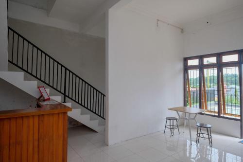 a room with a staircase and a table and chairs at RedDoorz near De La Salle Manado in Manado