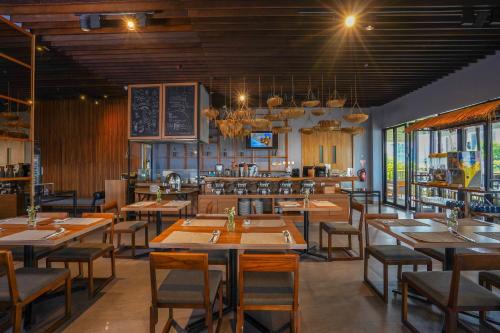 un restaurante con mesas y sillas de madera y una cocina en BATIQA Hotel Lampung, en Bandar Lampung