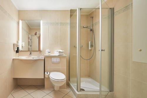 a bathroom with a shower and a toilet and a sink at Strandhotel an der Ostsee in Weissenhäuser Strand