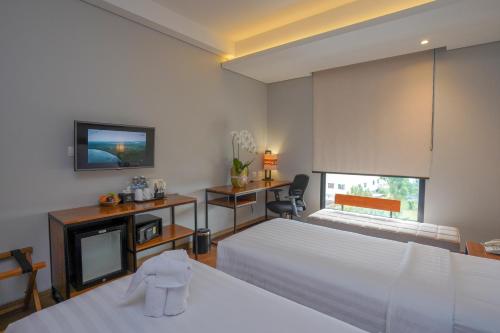 BATIQA Hotel Lampung في بندر لامبونغ: غرفة فندقية بسريرين وتلفزيون