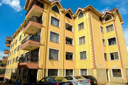 a yellow building with cars parked in front of it at Cozy and Elegant Studio in Nairobi