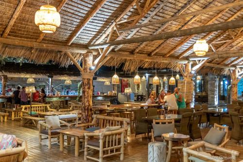 un restaurante con mesas y sillas y un bar en Porto Koundouros Beach and Villas, en Koundouros
