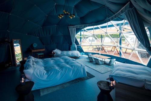 een blauwe kamer met 2 bedden en een groot raam bij ISUMI Glamping Resort ＆Spa SOLAS in Isumi