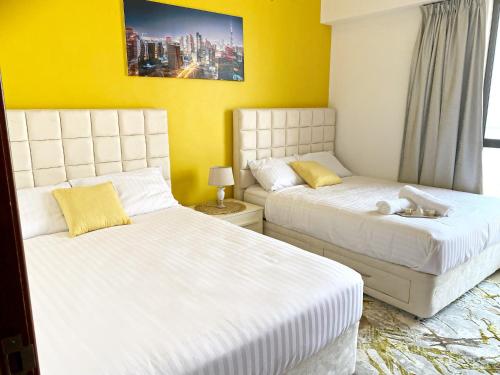 two beds in a room with yellow walls at Full Sea View 2 bedroom Apartment in Dubai Marina JBR in Dubai
