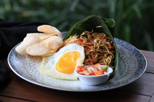 a plate of food with an egg and a sandwich at Natya Hotel Tanah Lot in Tanah Lot