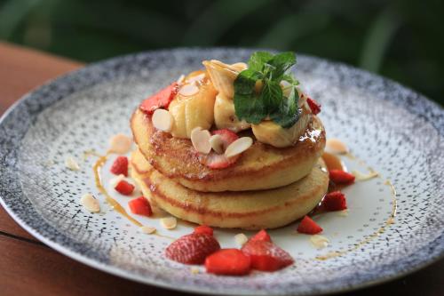 a stack of pancakes with strawberries on a plate at Natya Hotel Tanah Lot in Tanah Lot