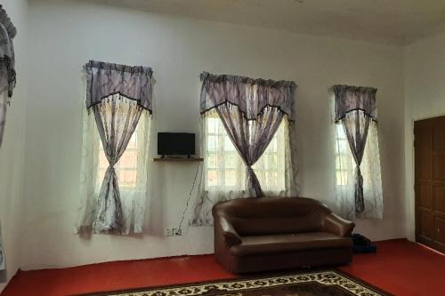 a living room with a couch and two windows at OYO Home 90723 Green Leaf Guest Lodge Kk in Kota Kinabalu