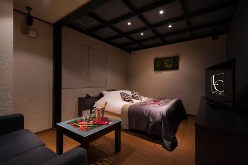 a bedroom with a bed and a table with a couch at Hotel LUNE CLAIRE (Adult Only) in Chikuma