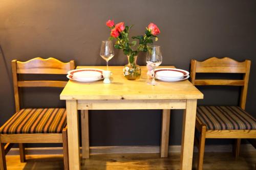 a wooden table with two chairs and a vase with flowers at Apartment for a short rent in KaunasButas trumpalaikei nuomai Kaune in Kaunas