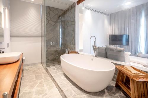 ein Badezimmer mit einer großen weißen Badewanne und einer Dusche in der Unterkunft YalaRent Red Sea glory villa-private pool & jacuzzi in Eilat