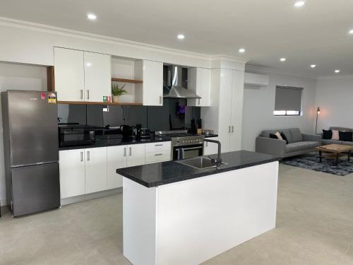 a kitchen with white cabinets and a stainless steel refrigerator at Lux Modern 4 Bedroom House Central CBD in Broken Hill