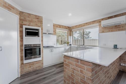 - une cuisine avec des appareils blancs et un mur en briques dans l'établissement Quality Apartments Banksia Albany, à Albany