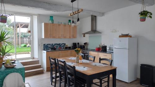 a kitchen with a table and a white refrigerator at Maison avec jardin, près plages du débarquement, table ping pong, à 800 m d' Omaha beach adaptée jeunes enfants in Vierville-sur-Mer